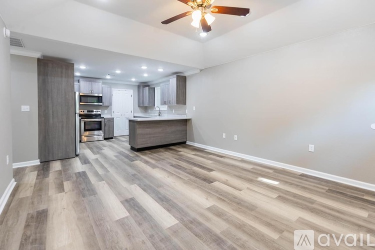 A spacious kitchen with wood flooring and a ceiling fan.