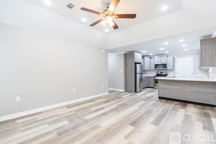 A spacious room with a ceiling fan and wooden flooring.