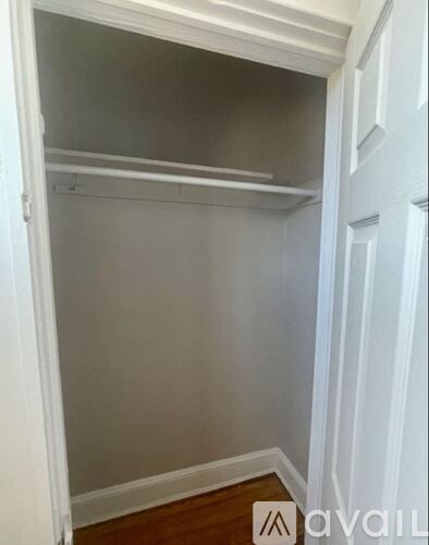 A white closet with a wooden floor and a white door.