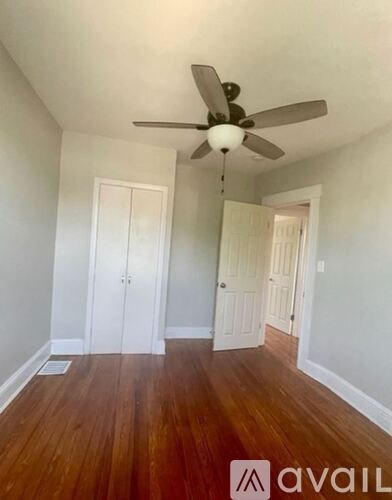 A room with a ceiling fan and wooden floors.