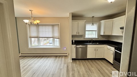 A kitchen with white cabinets and a window with blinds.