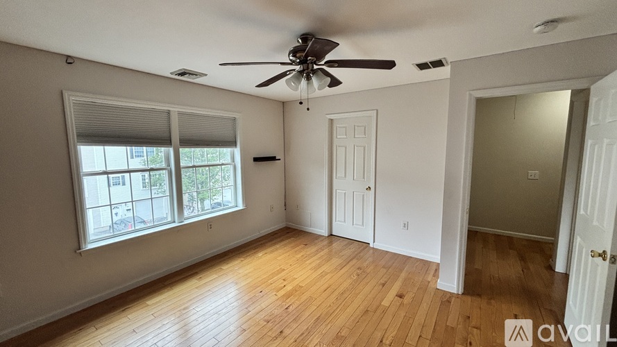 A room with a ceiling fan and wooden flooring.