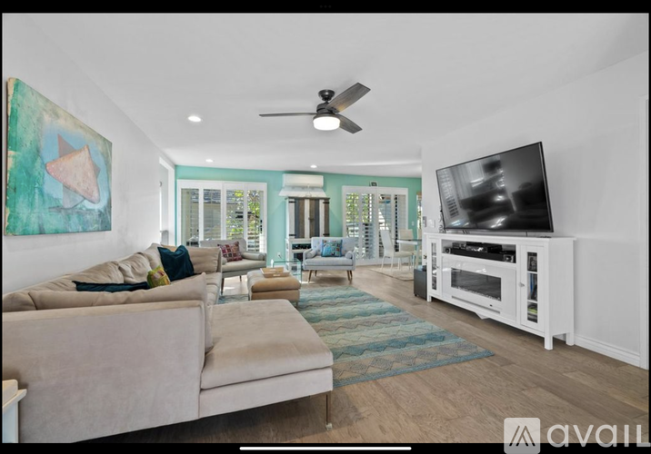 A living room with a beige couch, a television, and a painting on the wall.