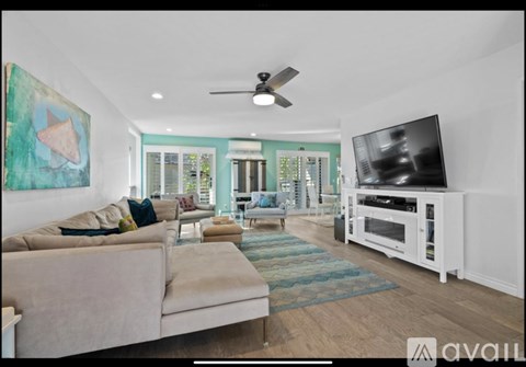 A living room with a beige couch, a television, and a painting on the wall.
