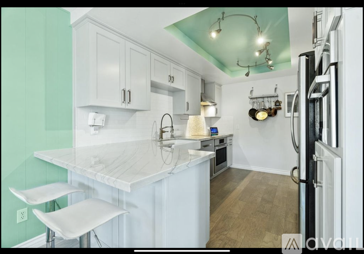 A kitchen with white cabinets and a marble countertop.