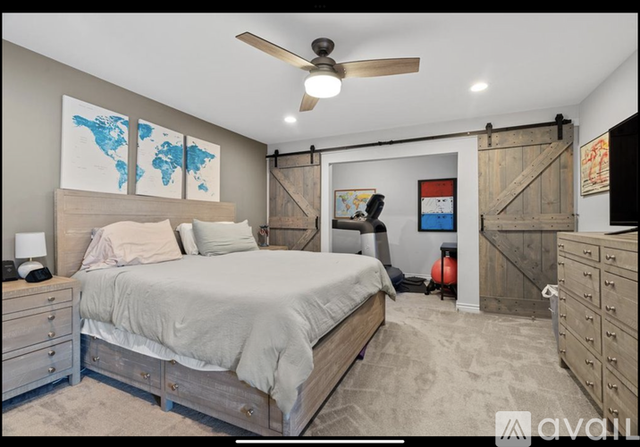 A bedroom with a large bed, a ceiling fan, and a world map on the wall.