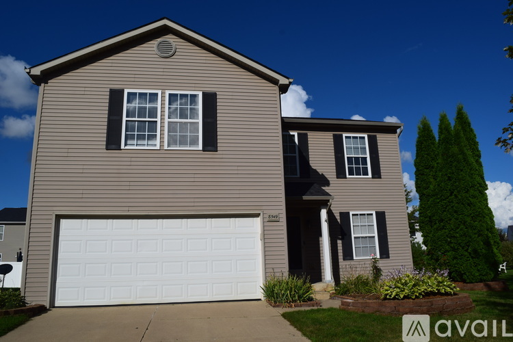 A house with a garage door and a tree in front.
