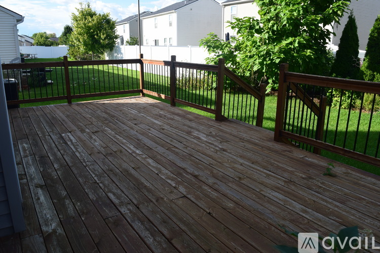 A wooden deck with a metal railing and a grassy area in the background.