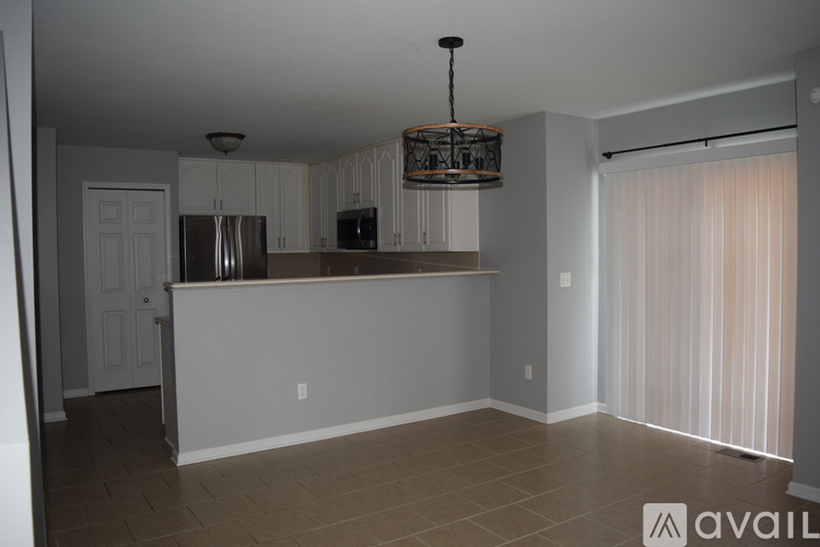 A kitchen with white cabinets and a black fridge.