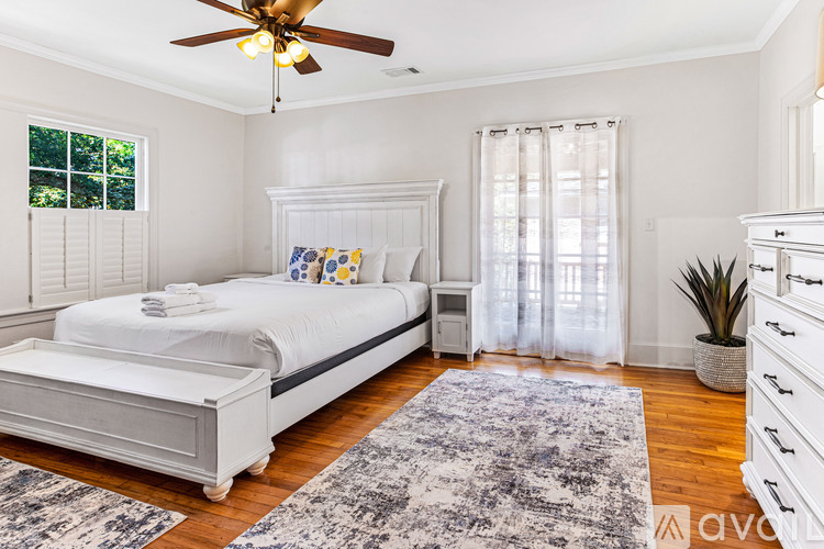A bedroom with a white bed and a ceiling fan.