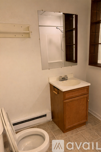 A white toilet with a wooden cabinet and a mirror above it.