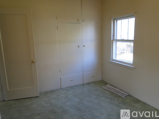 A room with a door, a window, and a carpeted floor.