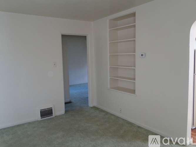 A room with a white wall and a door leading to a hallway.