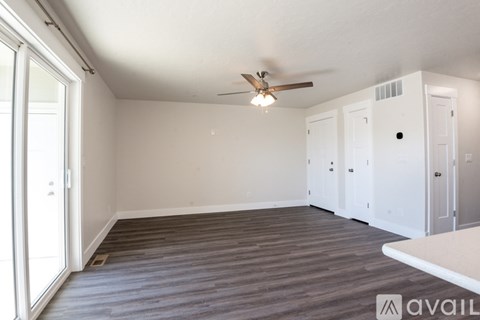 A room with a ceiling fan and wooden flooring.