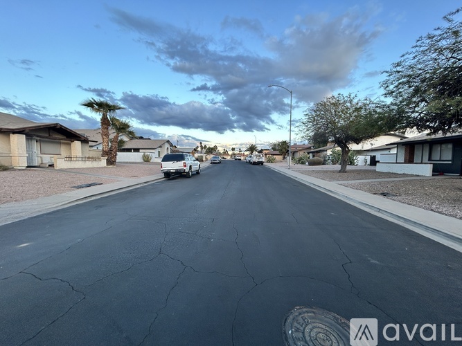 A street with houses on both sides and a car driving down the road.