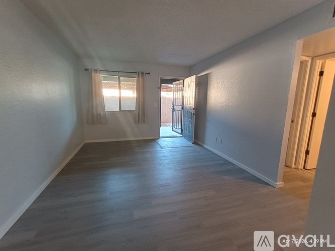 A spacious room with wooden flooring and white walls.