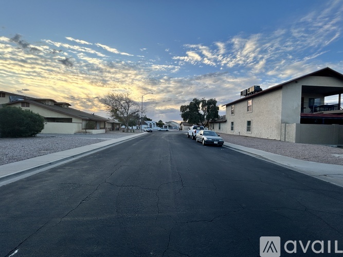 A street with cars parked on the side and houses on both sides.