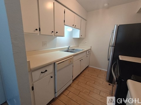 A kitchen with white cabinets and a black refrigerator.