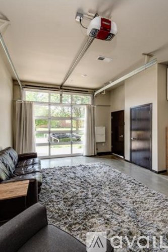 A living room with a grey carpet and a black couch.