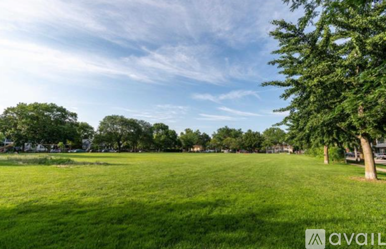 A grassy field with trees and a clear sky.
