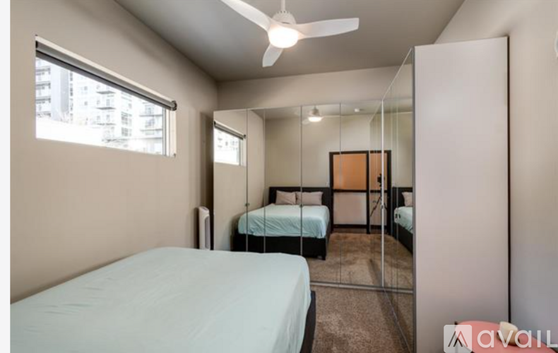 A bedroom with a bed, mirror, and ceiling fan.