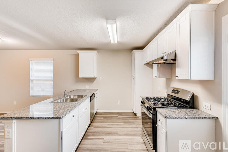 A kitchen with white cabinets and a granite countertop.