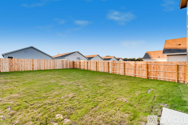A backyard with a wooden fence and green grass.