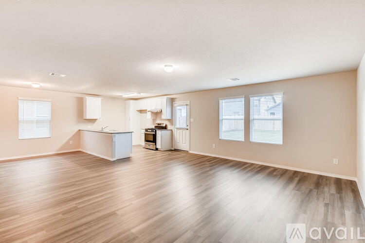 A spacious room with wooden flooring and white walls.