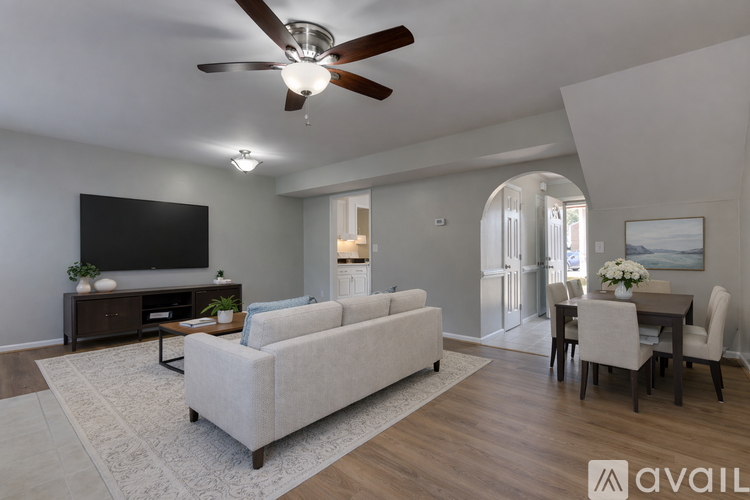 A living room with a white couch and a television on the wall.