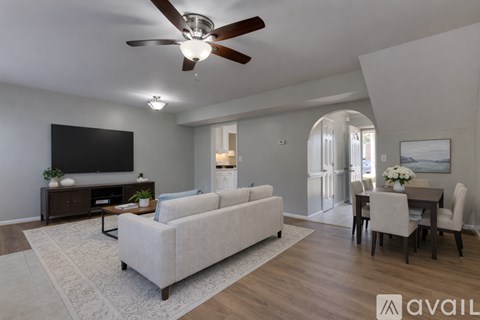 A living room with a white couch and a television on the wall.