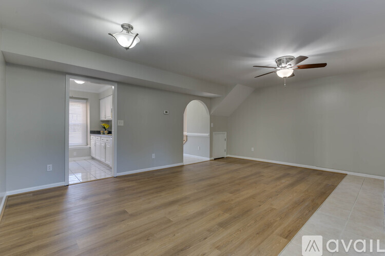 A spacious room with a ceiling fan and hardwood flooring.