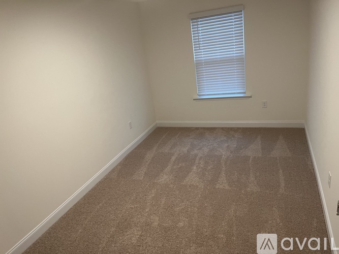 A room with a carpeted floor and a window with blinds.