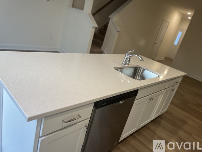 A modern kitchen with a white countertop and a stainless steel sink.