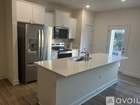 A kitchen with white cabinets and a stainless steel refrigerator.