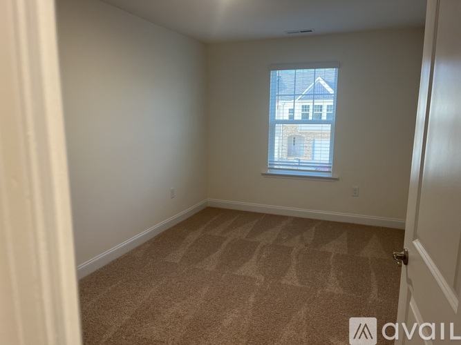 A room with a carpeted floor and a window showing a building outside.