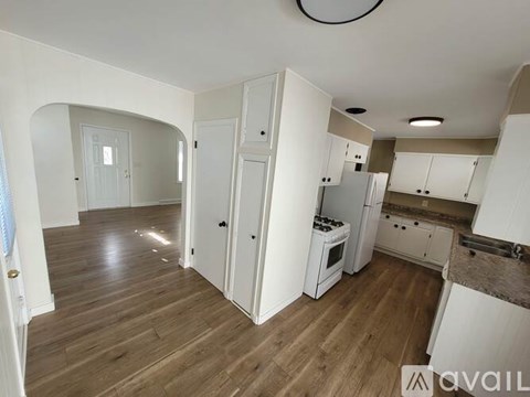 A kitchen area with white cabinets and a wooden floor.