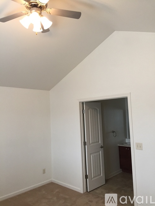 A room with a ceiling fan and a door leading to another room.