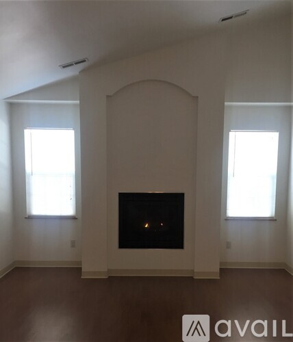A living room with a fireplace and two windows.