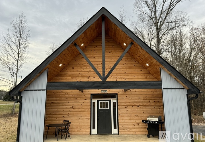 A wooden cabin with a black door and a small table and chairs outside.