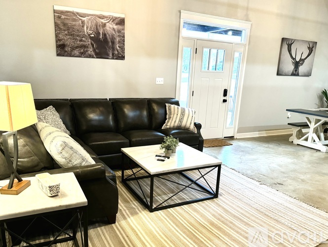 A living room with a black couch, a white coffee table, and a rug.