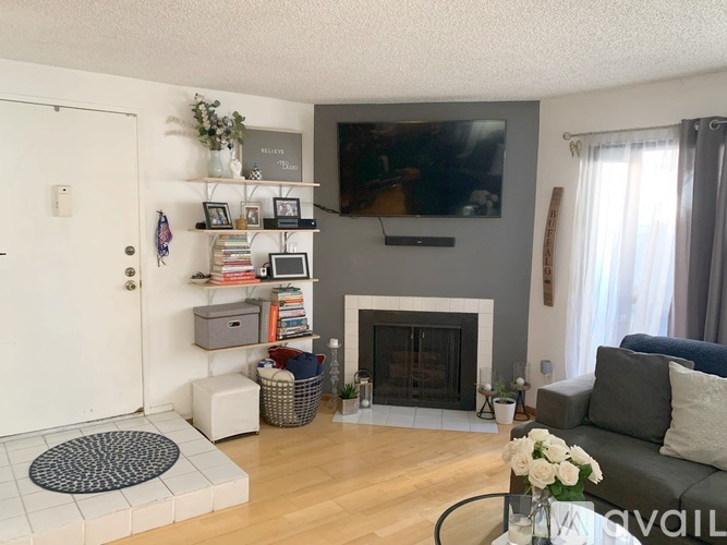 A living room with a fireplace and a flat screen TV mounted on the wall.