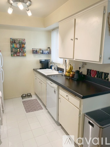 A kitchen with white cabinets and a black counter top.