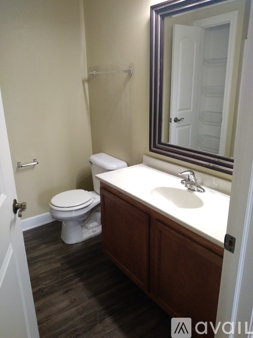 A bathroom with a toilet, sink and mirror.