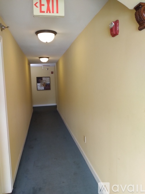 A long hallway with an exit sign on the ceiling.
