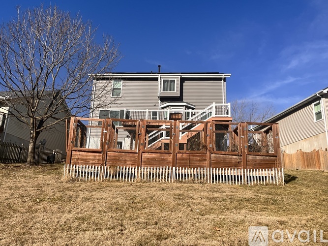 A house with a deck and a tree in the front yard.