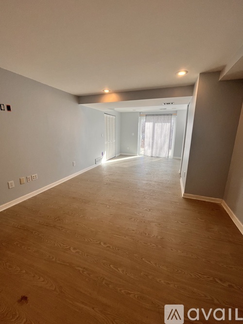 A spacious room with wooden flooring and a doorway leading to another room.