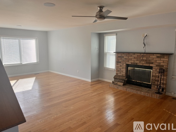 A living room with a fireplace and a fan on the ceiling.