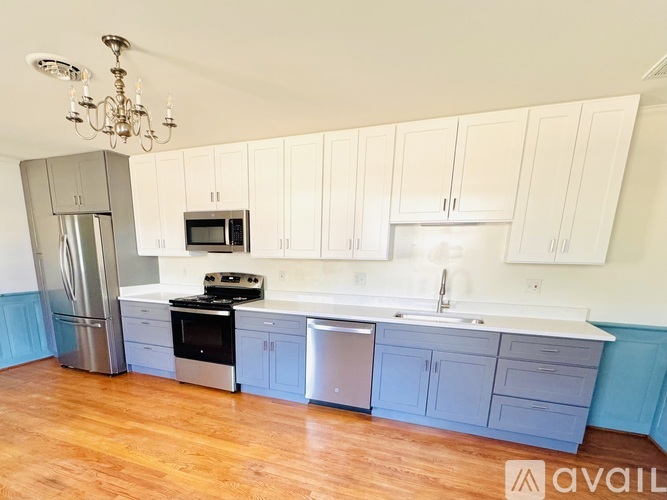 A kitchen with white cabinets and a wooden floor.