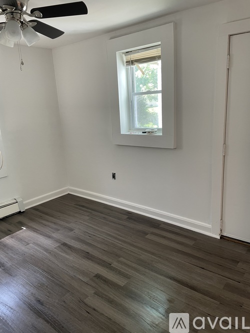 A room with a window and a fan on the ceiling.