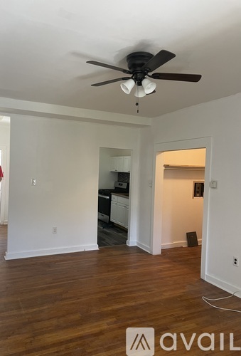 A room with a ceiling fan and wooden floors.